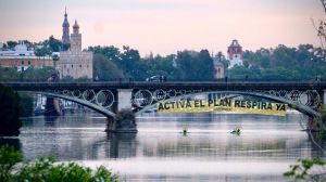 "REinventa Sevilla": Escaladores de Greenpeace se descuelgan con una pancarta en el puente de Triana
