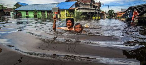 Unos niños caminan entre las aguas de las inundaciones en Palangka Raya, en Kalimantan Central, Indonesia
